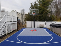 Blue basketball court with custom logo in tight yard space in Braintree, MA.