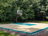 Residential basketball court in Brockton, MA with a surface tiled in sand and emerald green colors, featuring a custom Celtics log..