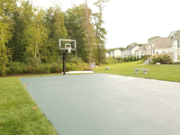Painted concrete base and already installed goal systems for residential basketball court in Dartmouth, MA, waiting for tile surface to finish it.