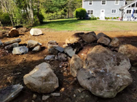Court site in Dover, MA being cleared and excavated, showing large rocks and boulders needing to be removed before a court base can be created.