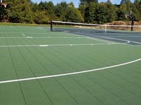View from the ground of most of olive and slate basketball and tennis court in Easton, MA, focused on the central net.