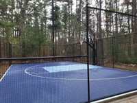 Most of complete basketball court from front angle toward hoop. Custom name logo on royal blue, with ice blue key, resurfaced onto existing asphalt court in Marion, MA.