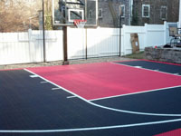 Black and red basketball court in tiny backyard, planned in winter and installed by early spring, in Hingham, MA.