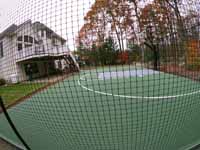Olive green and grey basketball court with hoop and fencing in Hopkinton, MA.