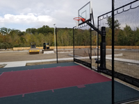 Hotel basketball court in Rhode Island, looking across hoop end toward unpaved future parking area.