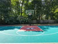 Emerald green and rust red home basketball court in Lynnfield, MA, featuring custom Celtics logo.