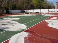 Decrepit tennis court in Manchester, NH repurposed and freshly surfaced as a basketball court in blue and red. Complete except paint over the exposed old surfaces around the new court. Shown here the old court surfaced after cleaning, patching and smoothing tp prepare for the new surface.