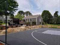 Charcoal and titanium Cape Cod backyard basketball court in Barnstable village of Marstons Mills, MA. Looking through fencing, an option this homeowner selected.
