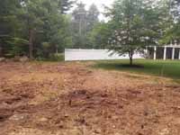 Backyard basketball court with graphite and red Versacourt surface in Middleborough, MA. Site shown here after trees had been removed and ground prepared, but before base and court installation.