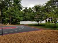 Backyard basketball court with graphite and red Versacourt surface in Middleborough, MA.