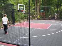 Milton, MA basketball court in a side yard, fit flush against a garage, featuring red and graphite Versacourt tiles.