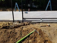 Runoff management work in progress for monochrome blue hilltop home basketball court in Milton, MA.