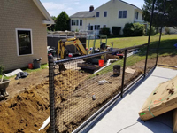 Runoff control work in progress for monochrome blue hilltop home basketball court in Milton, MA.
