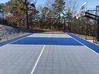 Hillside court primarily for pickleball, accessorized with a basketball goal and fencing, in Plymouth, MA. Finished view from the side.