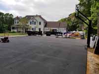 Home basketball court upgrade of old asphalt court in Cape Cod village of Pocasset in Bourne, MA. Shown here after installation of new goal system and uniform surfacing of patched asphalt.