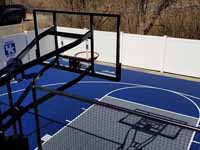 Royal blue and ice blue basketball court in Revere, MA. This was installed on existing concrete that included a cap on a filled in pool. Viewed from adjacent deck behind goal system.