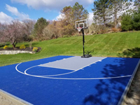 Almost the same view of Southborough, MA yard after royal blue and titanium court has been installed, rendering it much more colorful than with green grass alone.