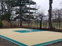 Photo from installation of a sand and emerald green residential backyard basketball court in Swampscott, MA.