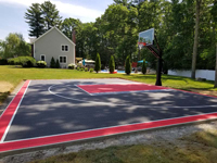 View from right end down length of charcoal and red basketball court with grey highlights in Taunton, MA.