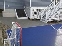 Small blue and grey basketball court in Braintree, MA, showing corner detail, associated hardscapes, and hockey net.