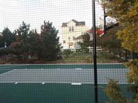 View through rebounder fence at green and gray basketball court in Plymouth, MA.
