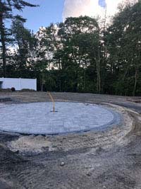 Mostly bare stretch of yard ready for landscaping and construction of a blue and gray residential basketball court in Easton, MA.