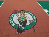 Closeup of Boston Celtics logo on a rust red background on a New Hampshire basketball court.