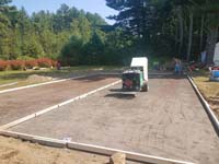 Construction of the base for a basketball court featuring Celtics logo, with fire pit, patio, and light for night play, in Londonderry, NH.
