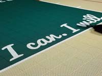 Closeup of some of the custom text on a tan and green basketball court in Londonderry, NH.