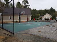 Green and black basketball court in Marion, MA, shown before completion of surrounding landscaping and pool.
