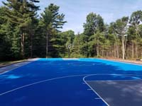Large commercial royal blue and titanium basketball court with golf seahorse logo at Bay Club in Mattapoisett, MA, as viewed from beneath hoop at one end, looking at the opposite end, showing the sheer size..