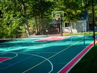 Home multicourt with basketball, adjustable net for sports like tennis and volleyball, optional night lighting, and even an in-ground trampoline not pictured her, in Pembroke, MA.