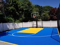 Colorful royal blue and yellow backyard basketball court in Stoneham, MA.