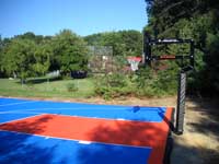 Blue and orange commercial sized backyard basketball court on asphalt base in Bellingham, Massachusetts.