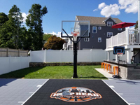 Boston Hoop Head court looking from left side of yard toward right, showing the remaining back lawn and the owner's newly installed outdoor entertaining area, along with most of the court and the hoop.