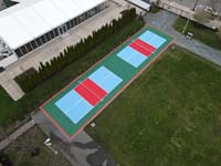 Drone view of complete double pickleball court in green, light blue, red, and orange, at Lawn on the D, adjacent to Westin Hotel, in Boston, MA.