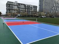 Double Boston pickleball court seen at an angle down length looking east toward D Street and apartment buildings.