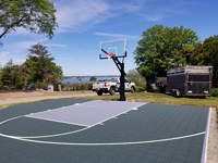 View across backyard basketball court front right to left rear, with water in background, on Cape Cod in Chatham, MA.