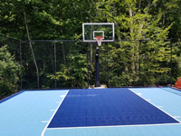 View straight at hoop of small light and navy blue backyard basketball court in Medway, MA.