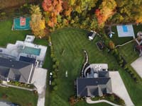 Adjacent home basketball courts from on high, with finished landscaping and a burst of fall foliage, in Middleton, MA.