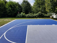 Closer view of basketball court surface from partway down right toward left side, showing blue and silver tiles in North Attleboro, MA.