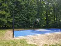 Backyard basketball court in village of Oakdale, Connecticut, in the historic town of Montville. Blue and silver surface with a custom logo that says Center Court with an orange basketball in place of the letter o.