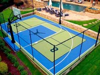Example of SnapSports tile basketball and pickleball multicourt surface in pale yellow-green and medium blue, with added fencing, goal and net systems, and custom logos.
