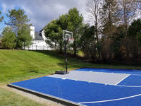 Angled view from the left side of the court toward the hoop, showing royal blue and silver basketball court in Southborough.