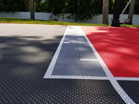 Closeup near center of basketball court in Taunton, MA, showing part of red key, charcoal main surface, titanium highlights, and white lines.
