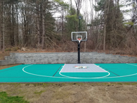 Completed backyard basketball court in green and silver, with landscape wall in background, in Upton, MA.