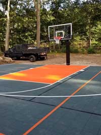 Graphite and orange home basketball court before fence installation in Walpole, MA.