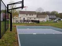 Green and black basketball court surface with hoop and basic rebounder in Agawam, MA.