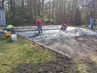 Cement work in construction of the base for a dark green and grey backyard basketball court in Agawam, MA.