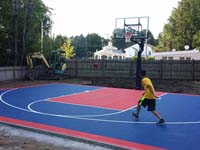Kid enjoying barely completed navy and red home basketball court in Canton, MA.